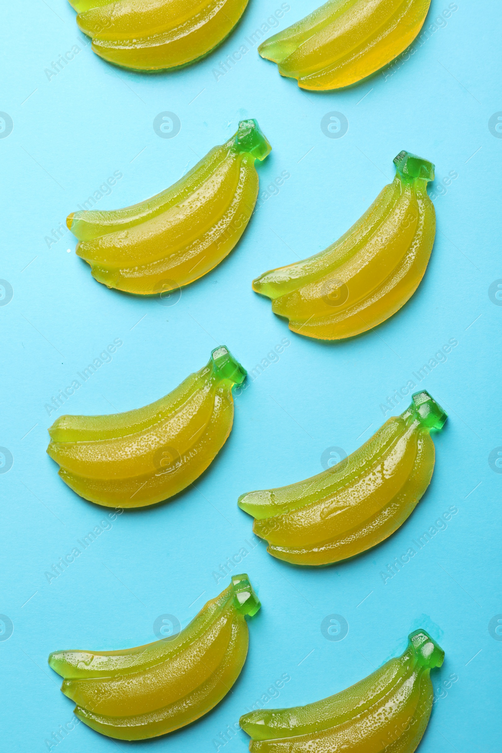 Photo of Delicious gummy banana candies on light blue background, flat lay