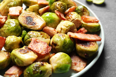 Delicious fried Brussels sprouts with bacon on table, closeup