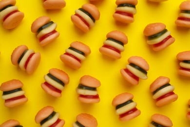 Tasty jelly candies in shape of burger on yellow background, flat lay