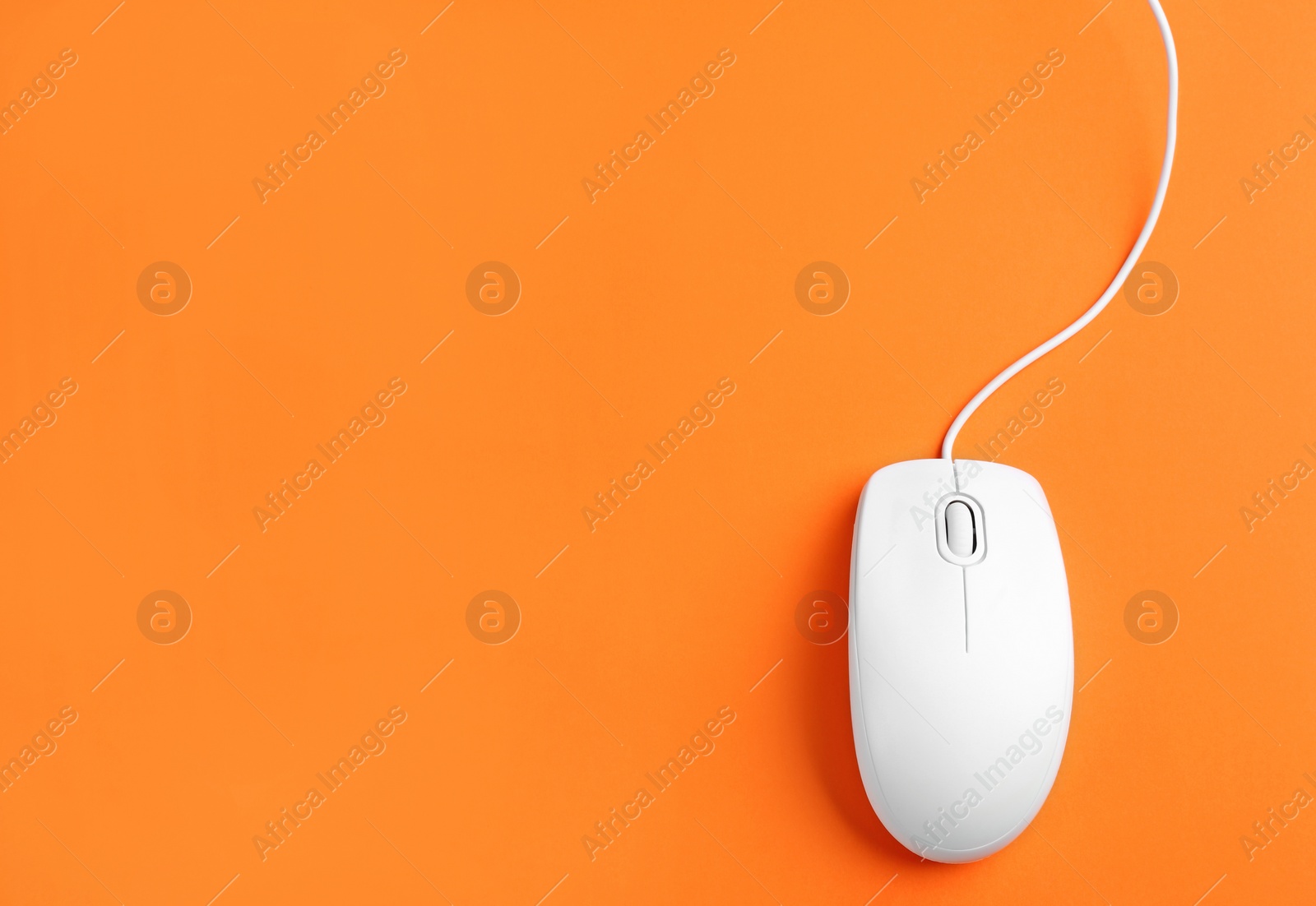 Photo of Modern wired optical mouse on orange background, top view. Space for text