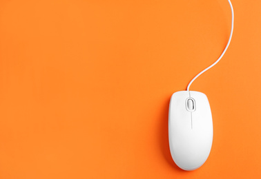 Photo of Modern wired optical mouse on orange background, top view. Space for text