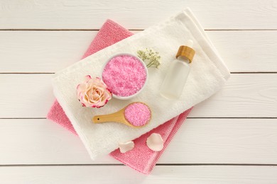 Aromatic sea salt and beautiful flowers on white wooden table, flat lay