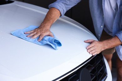 Photo of Man cleaning car hood with rag, closeup