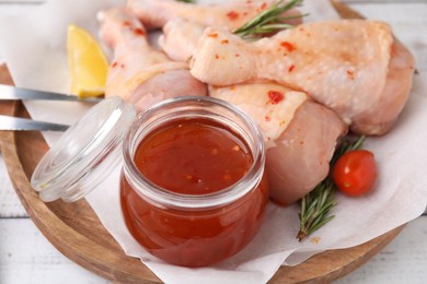Photo of Fresh marinade, raw chicken drumsticks, rosemary and tomato on white wooden table, closeup