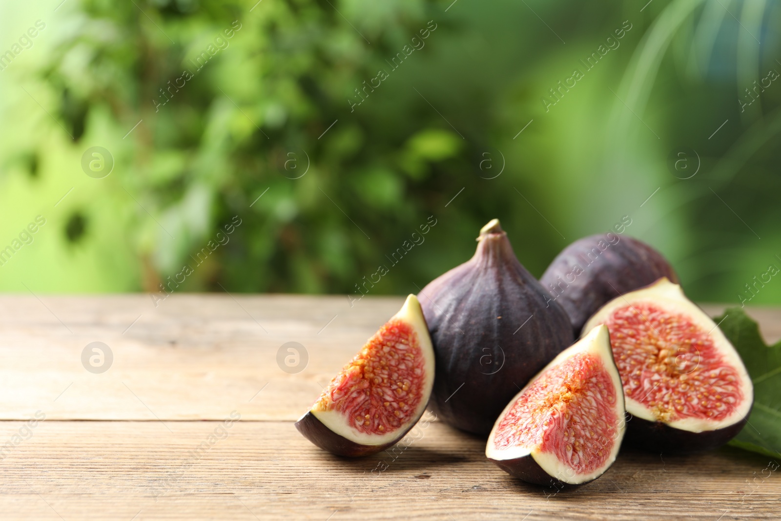 Photo of Fresh ripe figs on wooden table. Space for text