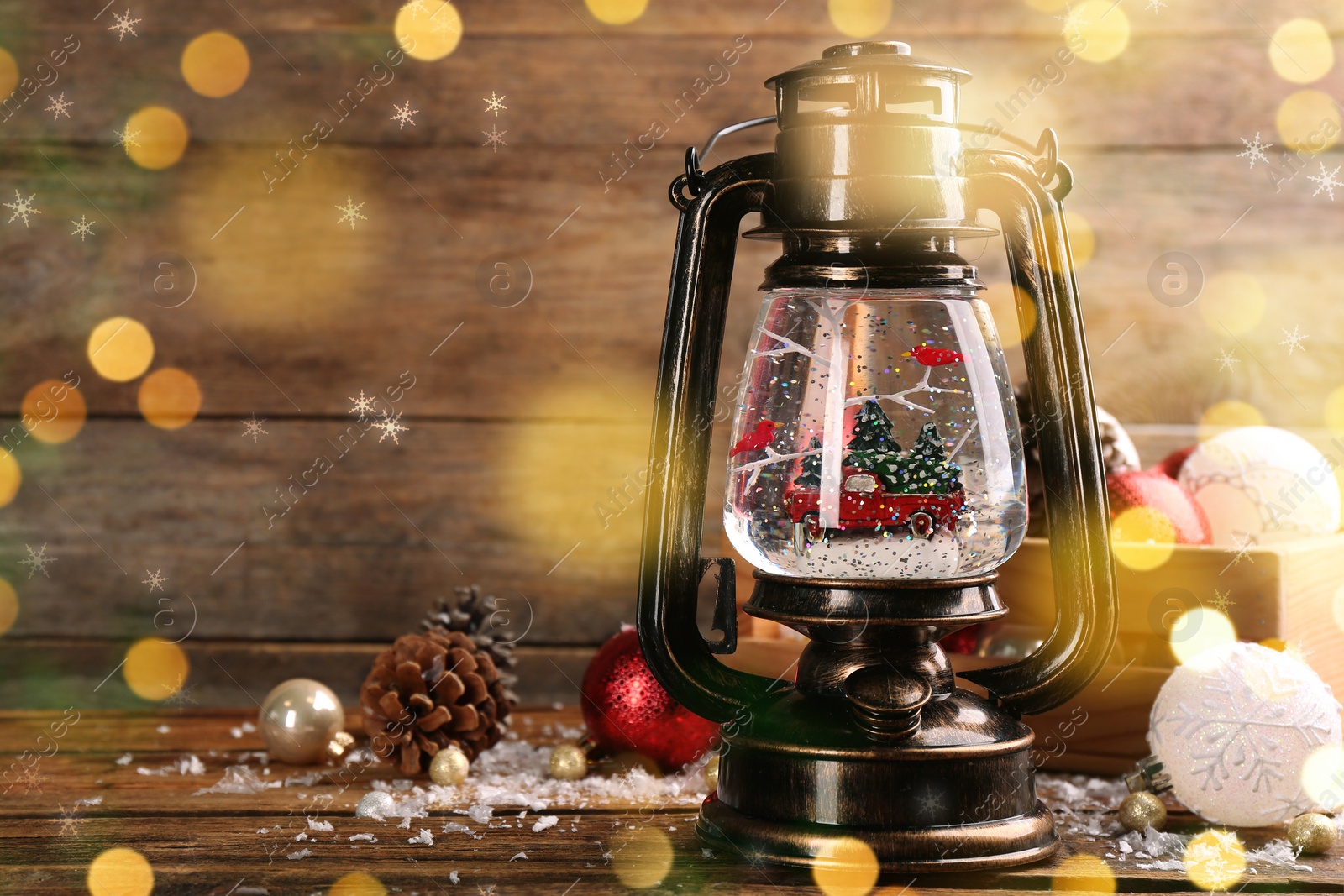 Image of Beautiful Christmas snow globe in vintage lantern and festive decor on wooden table, space for text. Bokeh effect