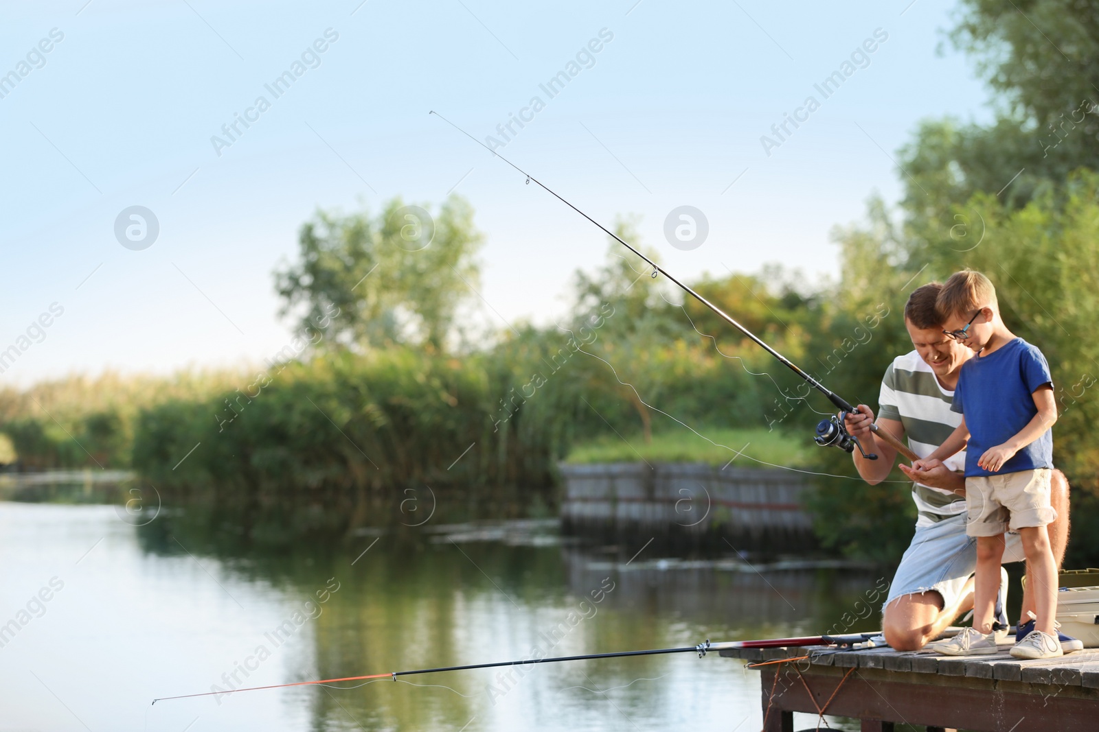 Photo of Dad and son fishing together on sunny day