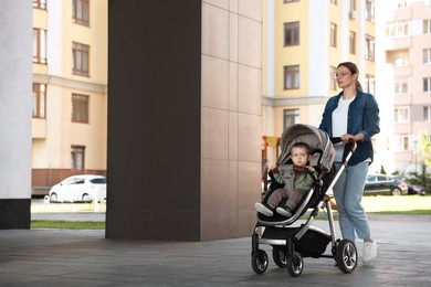 Photo of Beautiful nanny with cute little boy in stroller walking on city street