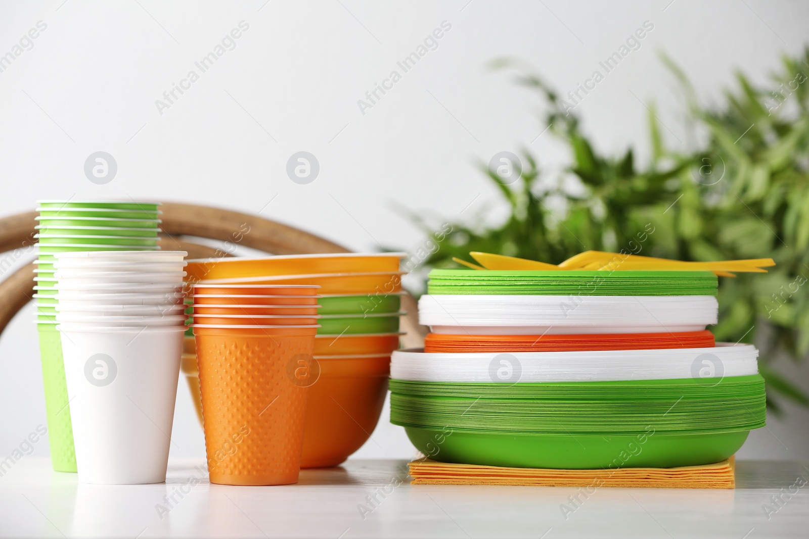 Photo of New plastic dishware on table against blurred background. Table setting