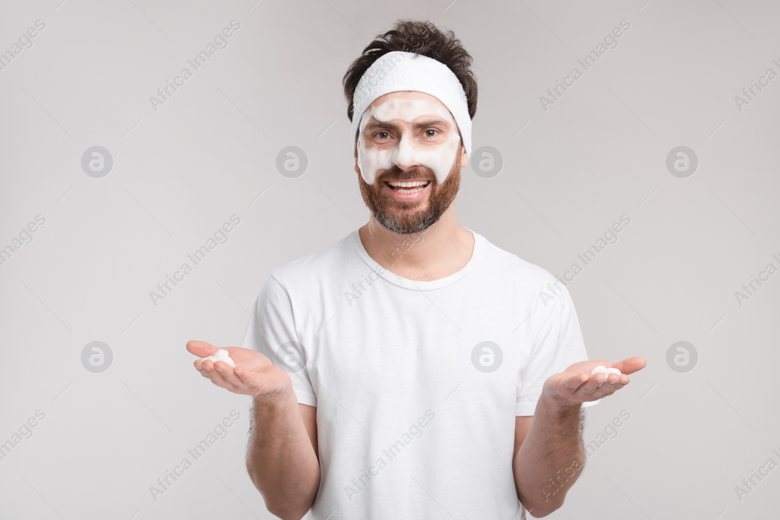 Photo of Man with headband washing his face on light grey background