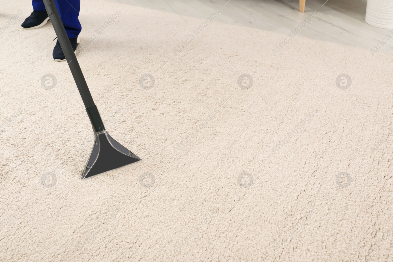 Photo of Man removing dirt from carpet with vacuum cleaner indoors, closeup. Space for text