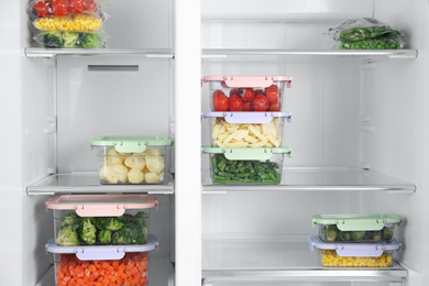 Photo of Plastic bags and containers with different frozen vegetables in refrigerator