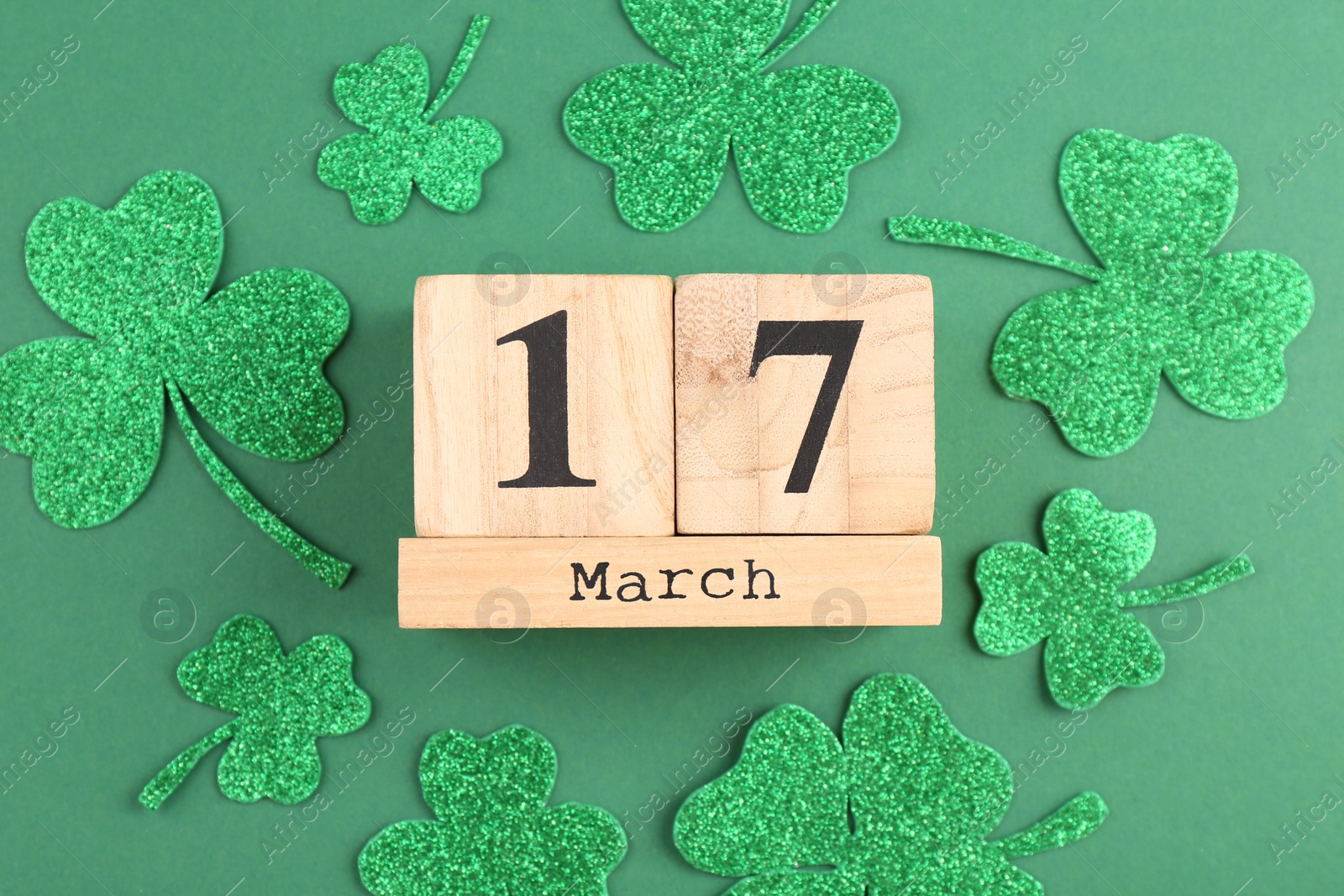 Photo of St. Patrick's day - 17th of March. Block calendar and decorative clover leaves on green background, flat lay