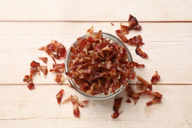 Pieces of tasty fried bacon in bowl on wooden table, top view