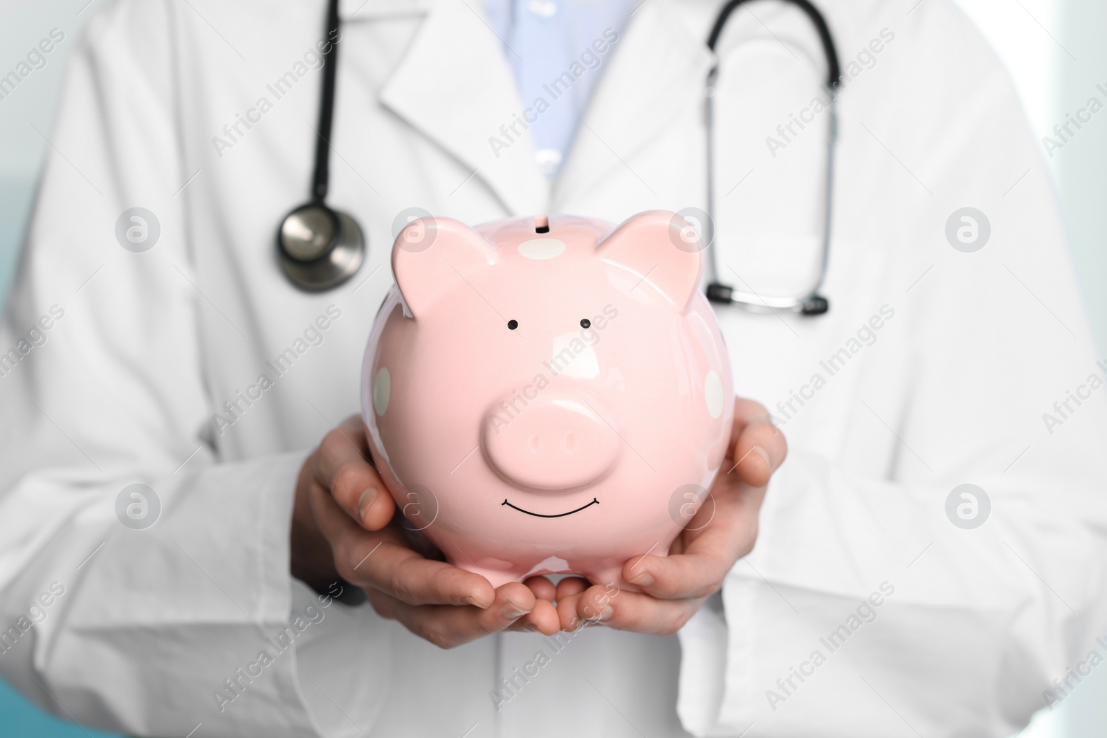 Photo of Doctor with piggy bank in hospital, closeup