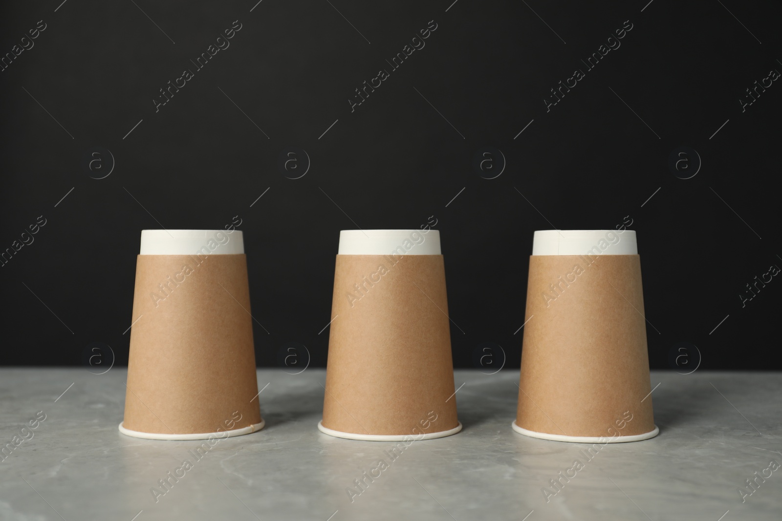 Photo of Shell game. Three paper cups on grey marble table