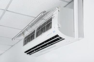 Photo of Modern air conditioner hanging on white wall
