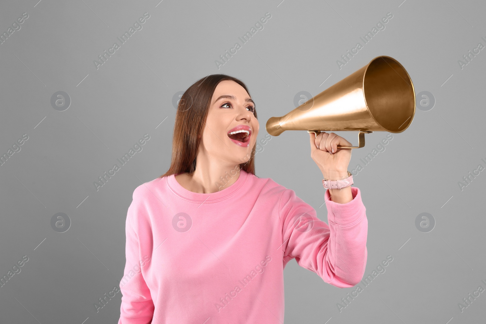 Photo of Young woman with megaphone on grey background