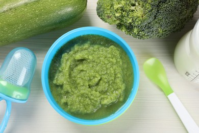 Healthy baby food. Bowl with delicious broccoli puree and ingredients on white wooden table, flat lay