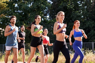 Photo of Group of people running outdoors on sunny day