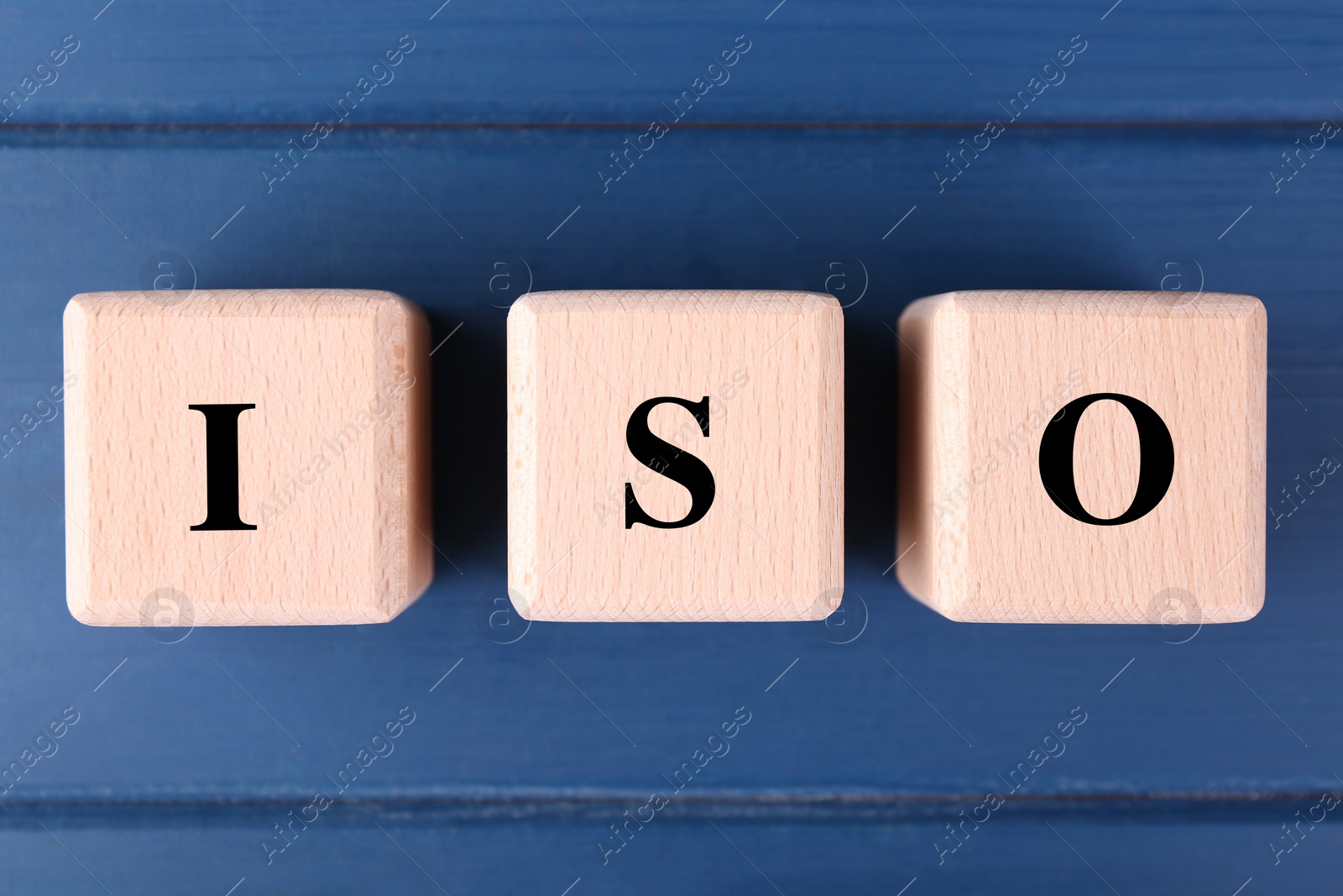 Photo of International Organization for Standardization. Cubes with abbreviation ISO on blue wooden table, top view