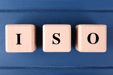 International Organization for Standardization. Cubes with abbreviation ISO on blue wooden table, top view
