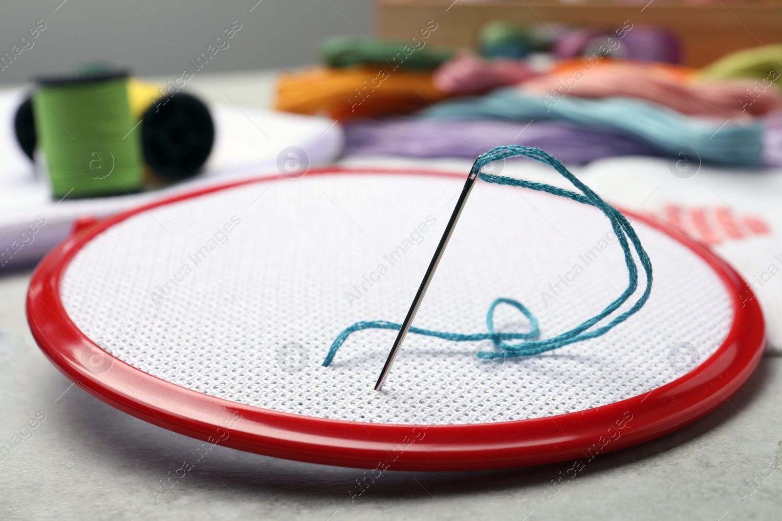 Photo of Embroidery hoop with fabric and needle on light grey
table, closeup