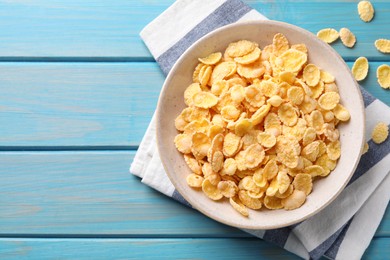 Photo of Tasty crispy corn flakes on light blue wooden table, flat lay. Space for text