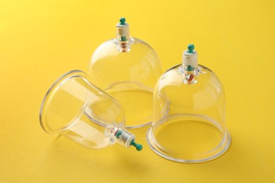 Photo of Plastic cups on yellow background, closeup. Cupping therapy
