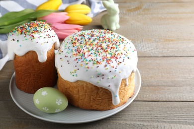 Photo of Easter cakes and color egg on wooden table, space for text
