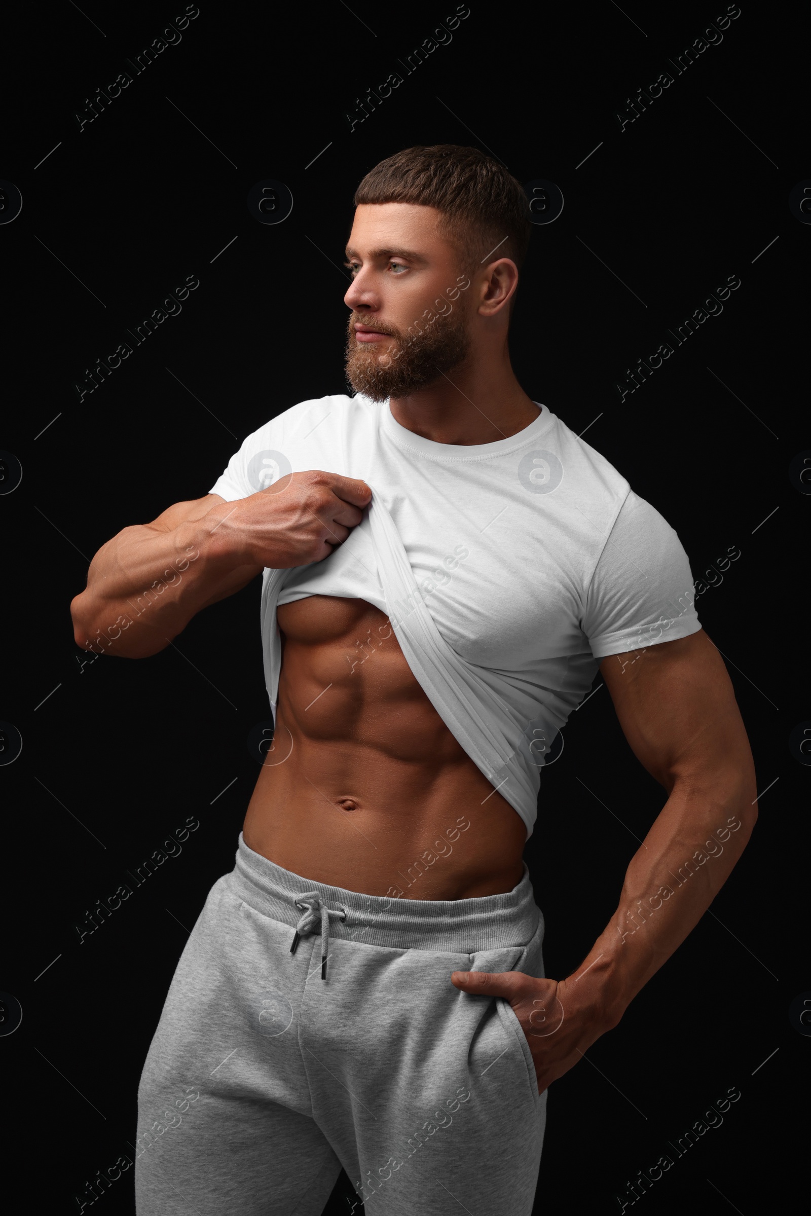 Photo of Young bodybuilder showing his muscular body on black background