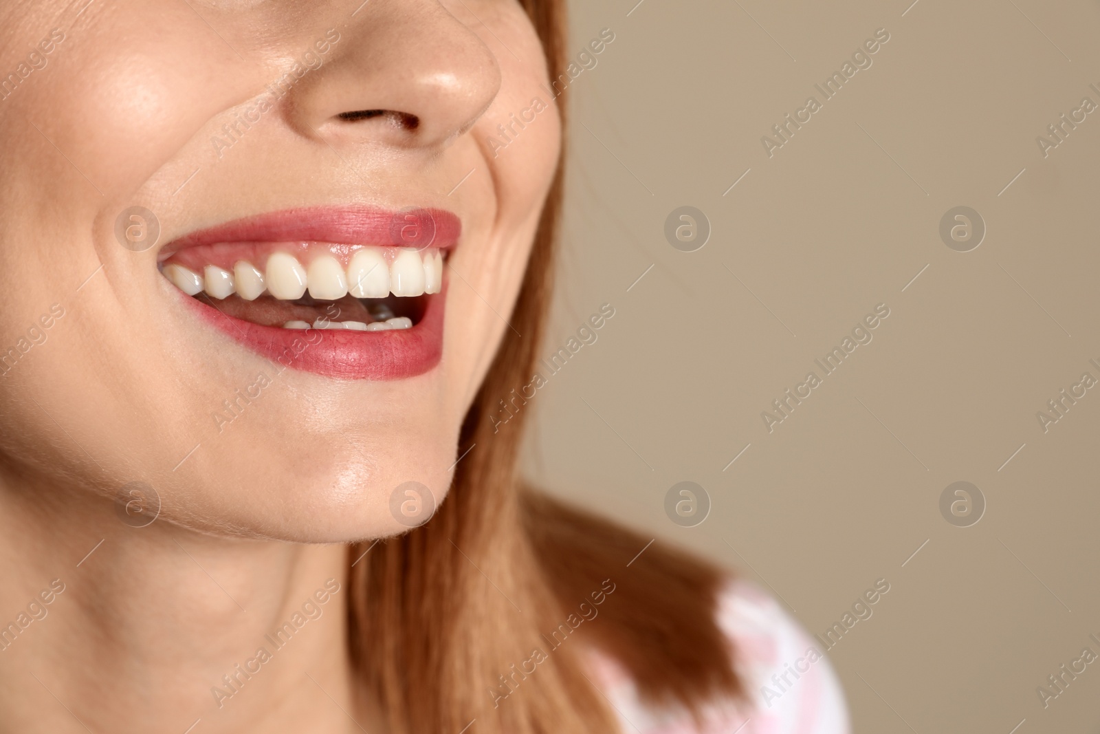 Photo of Smiling woman with perfect teeth on color background, closeup. Space for text