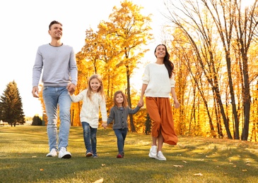 Photo of Happy family with little daughters walking in autumn park