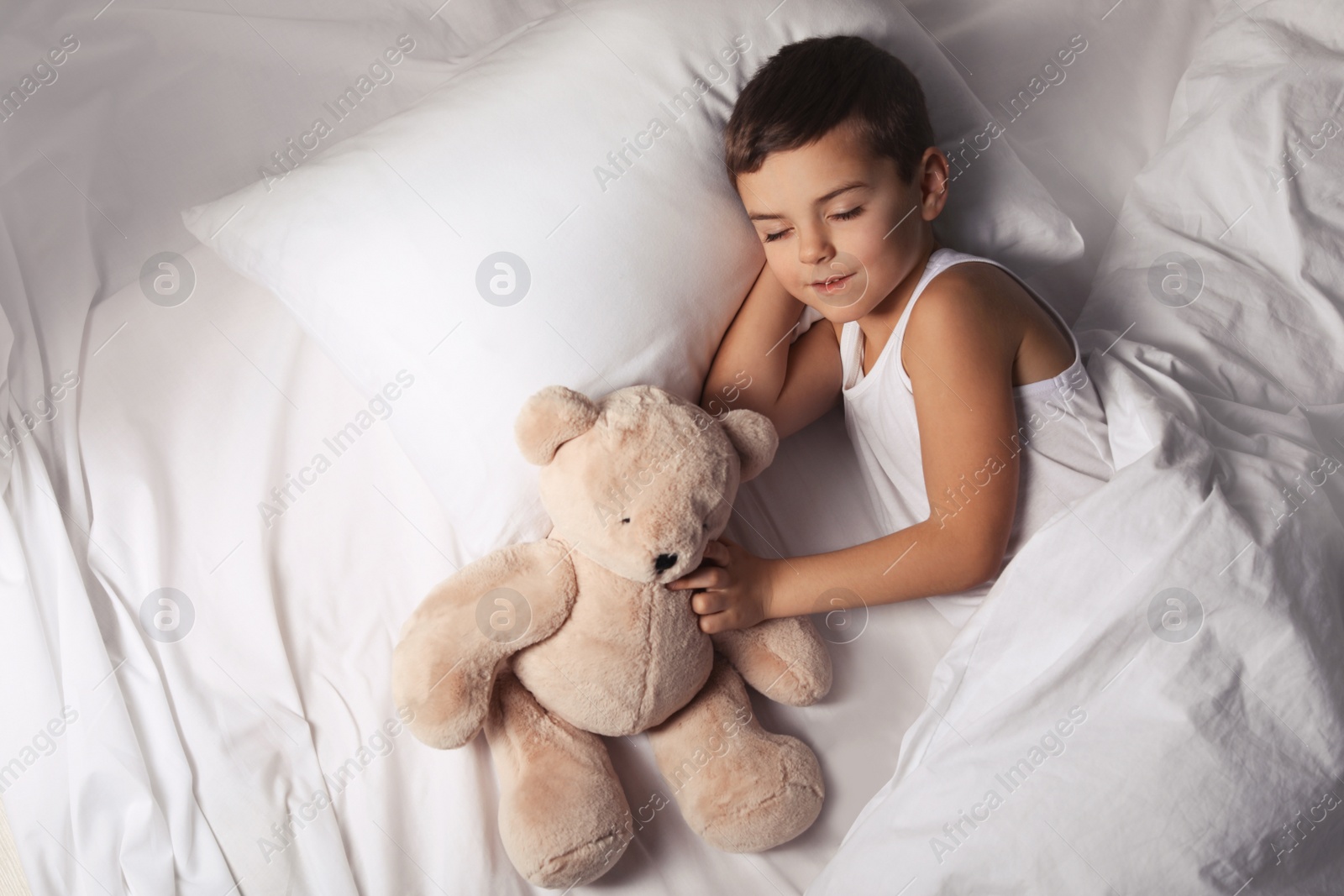 Photo of Little boy sleeping with teddy bear at home. Bedtime