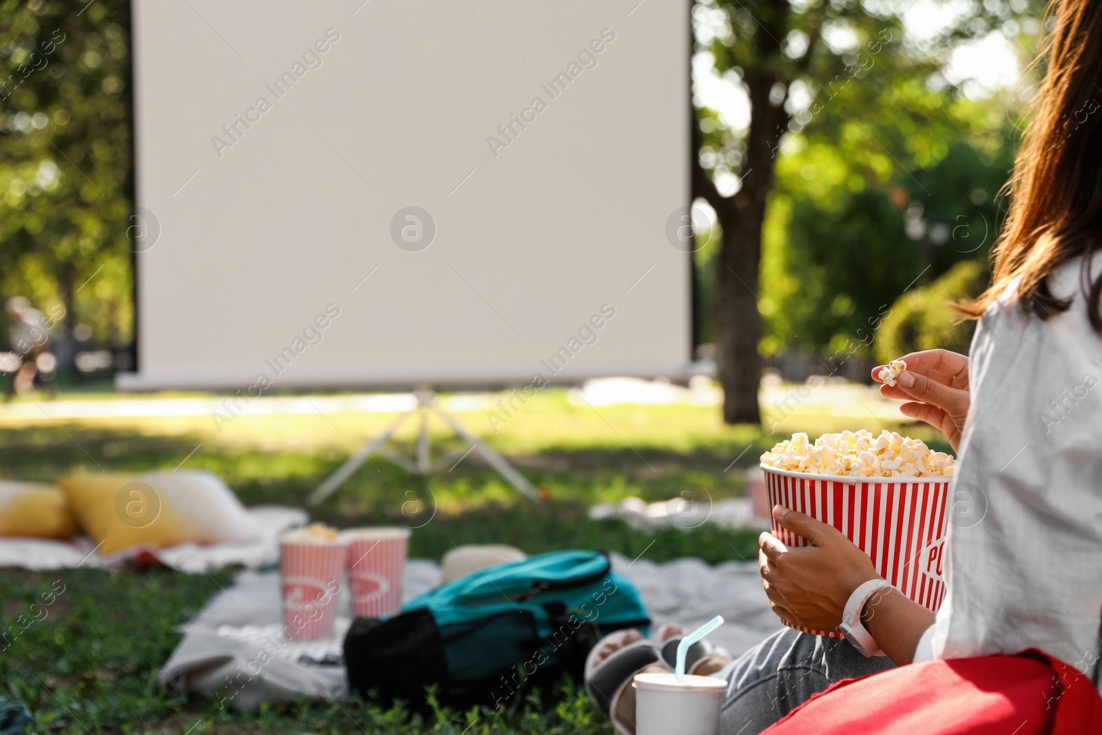 Photo of Woman with popcorn watching movie in open air cinema, closeup. Space for text