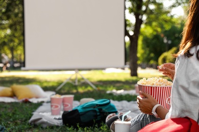 Woman with popcorn watching movie in open air cinema, closeup. Space for text