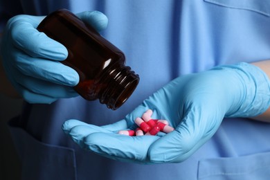 Doctor pouring pills from bottle onto hand, closeup view
