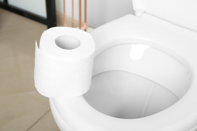 Photo of New paper roll on toilet seat in bathroom