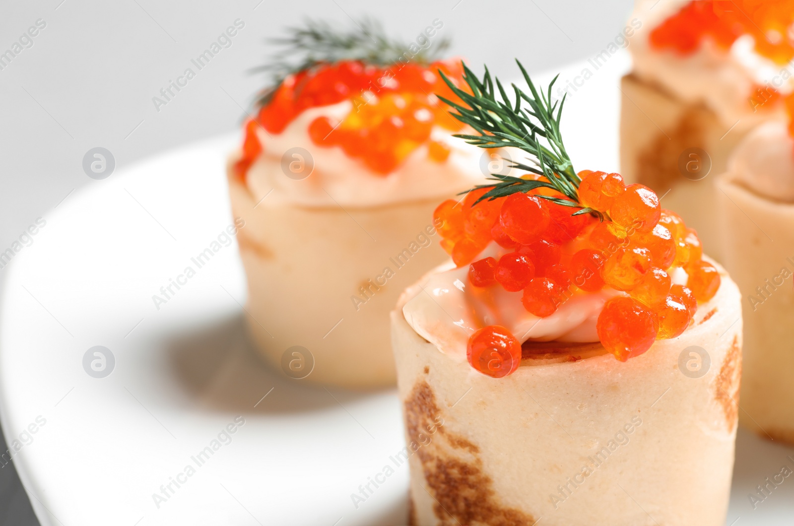 Photo of Delicious thin pancakes with red caviar, closeup