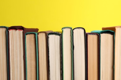 Different old hardcover books on yellow background, closeup