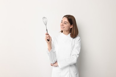 Professional chef with whisk on light background