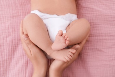 Photo of Mom with her baby in diaper on bed, closeup