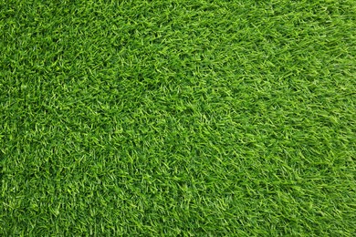 Green artificial grass as background, top view