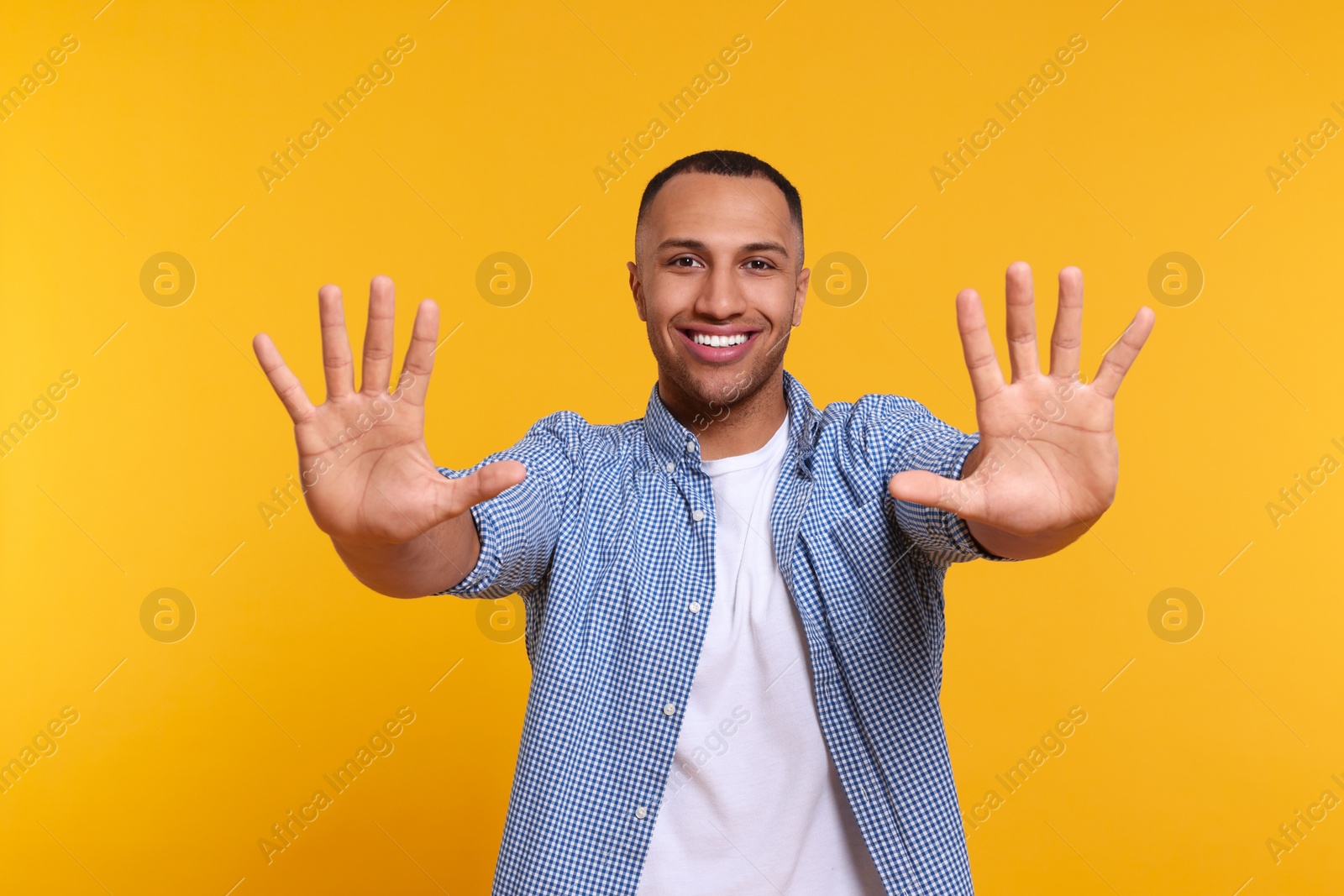 Photo of Man giving high five with both hands on yellow background