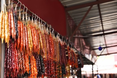 Bunches of different delicious churchkhelas hanging on rack at market, space for text