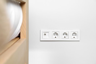 Power sockets on white wall indoors. Electrical supply