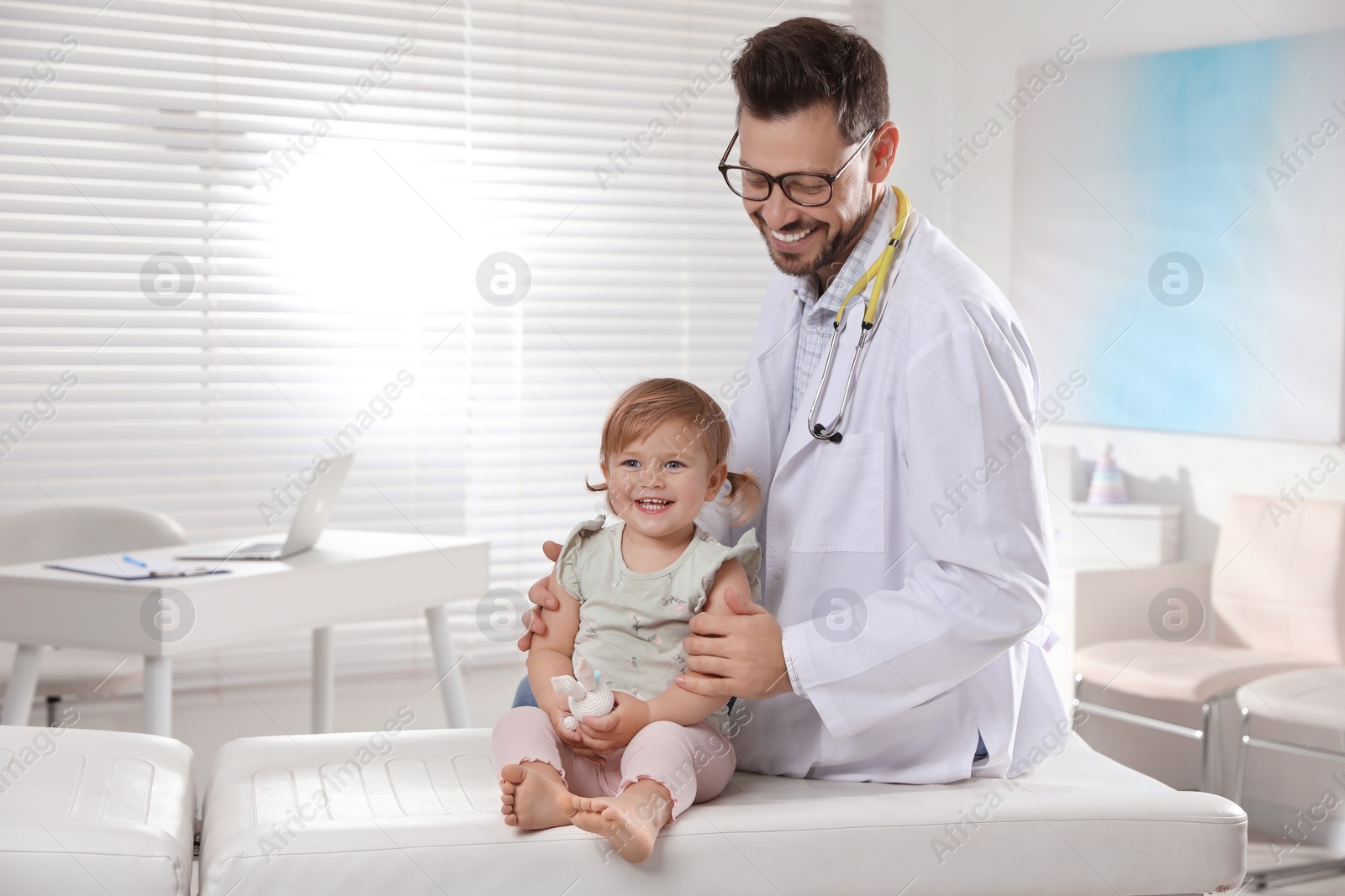 Photo of Pediatrician examining cute little baby in clinic