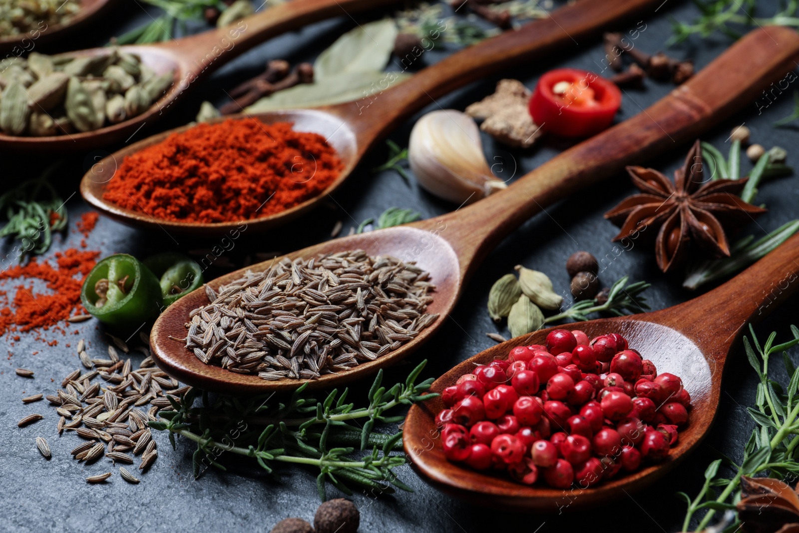 Photo of Different natural spices and herbs on black table, closeup