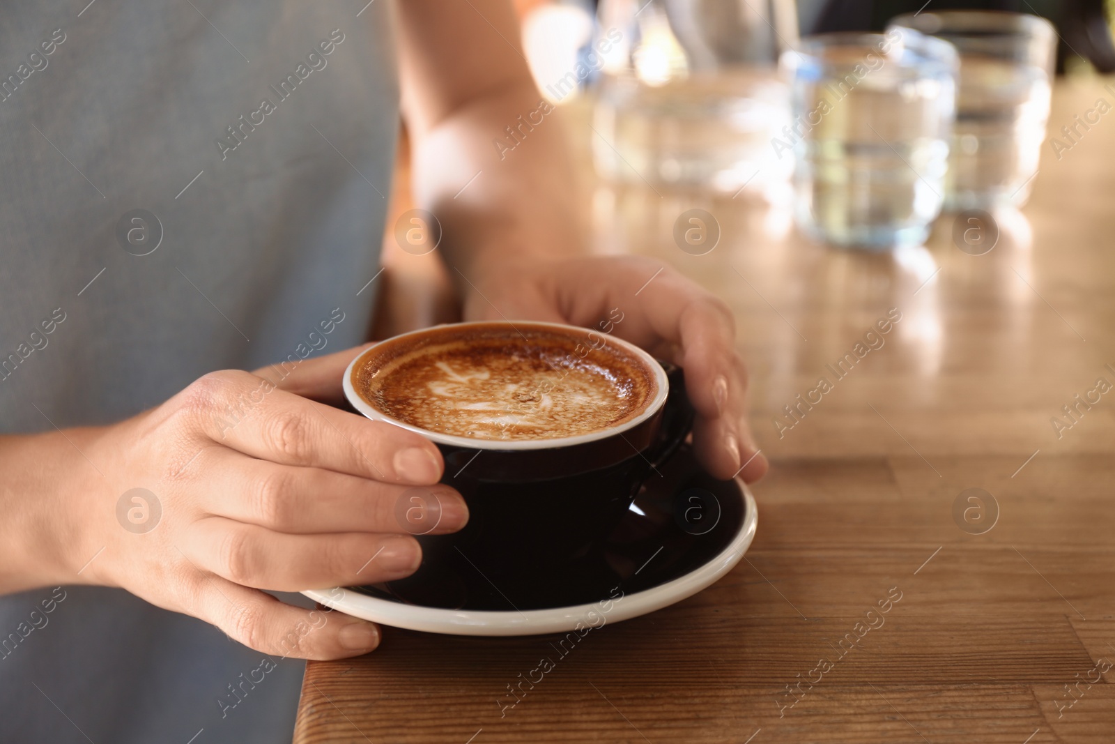 Photo of Woman with cup of fresh aromatic coffee at table, closeup