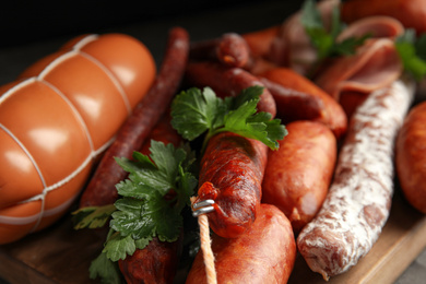 Different tasty sausages on wooden board, closeup